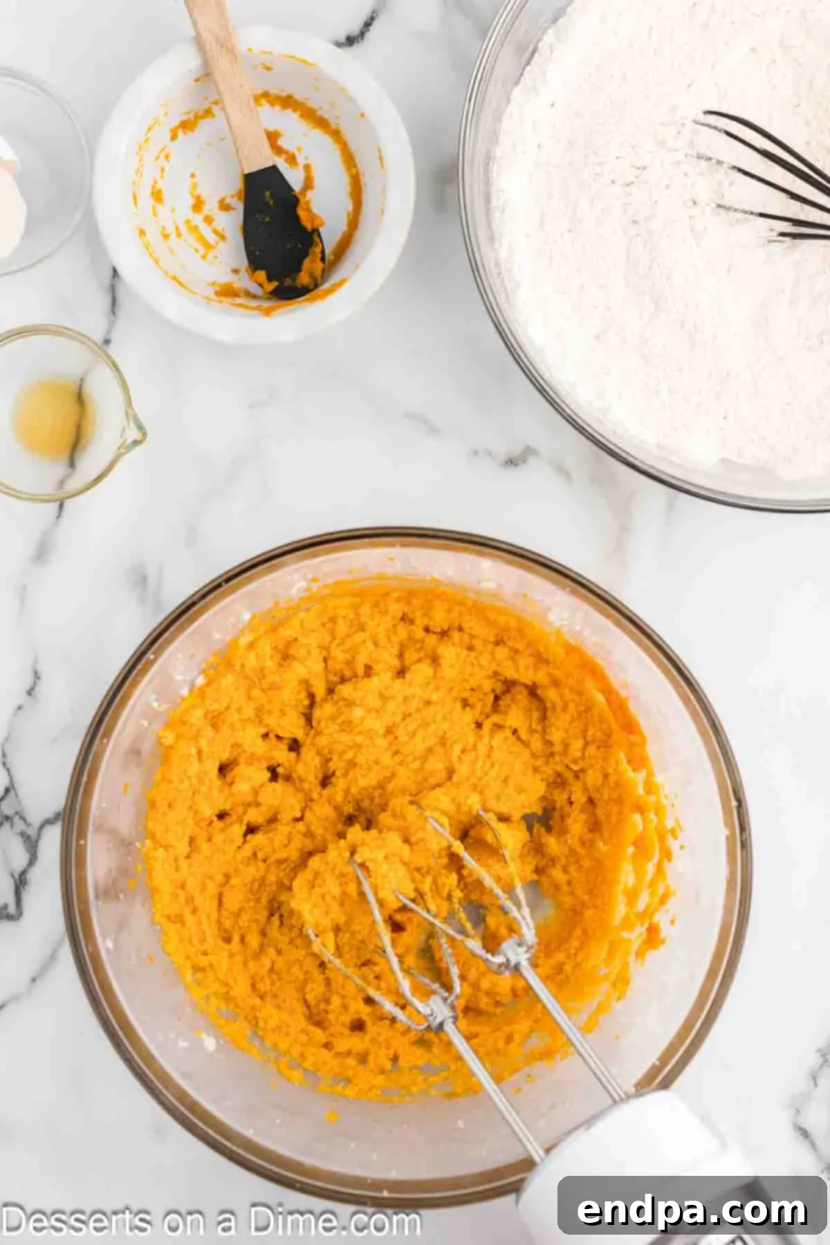 The pumpkin, egg, and vanilla mixture thoroughly combined with the butter and sugar, resulting in a smooth, evenly blended, and orange-hued cookie batter.