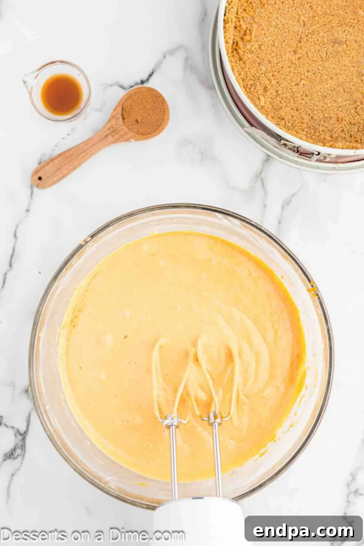 Velvet Pumpkin Spice Cheesecake 5 Pure pumpkin puree and large eggs being added to the creamy mixture of cream cheese and brown sugar in a mixing bowl, preparing for the next stage of the cheesecake filling.