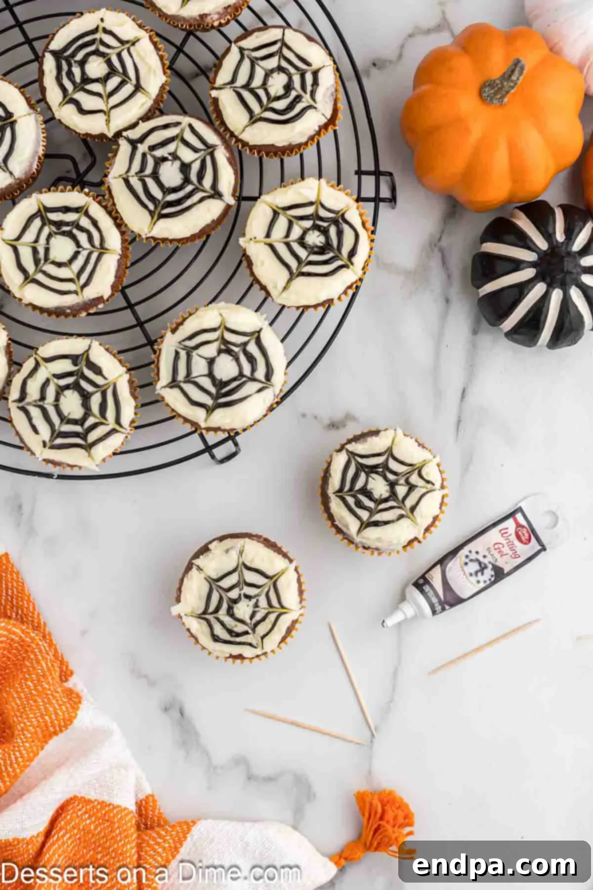 A toothpick being used to draw lines through the concentric frosting circles on a cupcake, creating the iconic spider web design.