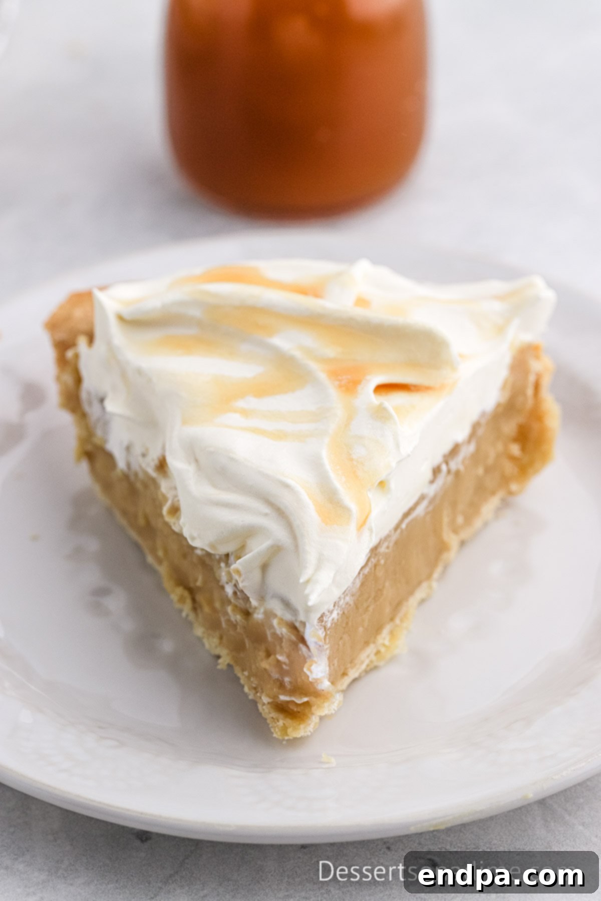 Golden Butterscotch Delight 8 A perfectly sliced piece of homemade Butterscotch Pie, showcasing its creamy golden filling and beautifully flaky crust. The slice is topped with a generous swirl of whipped cream and is ready to be enjoyed as a delightful, indulgent dessert.