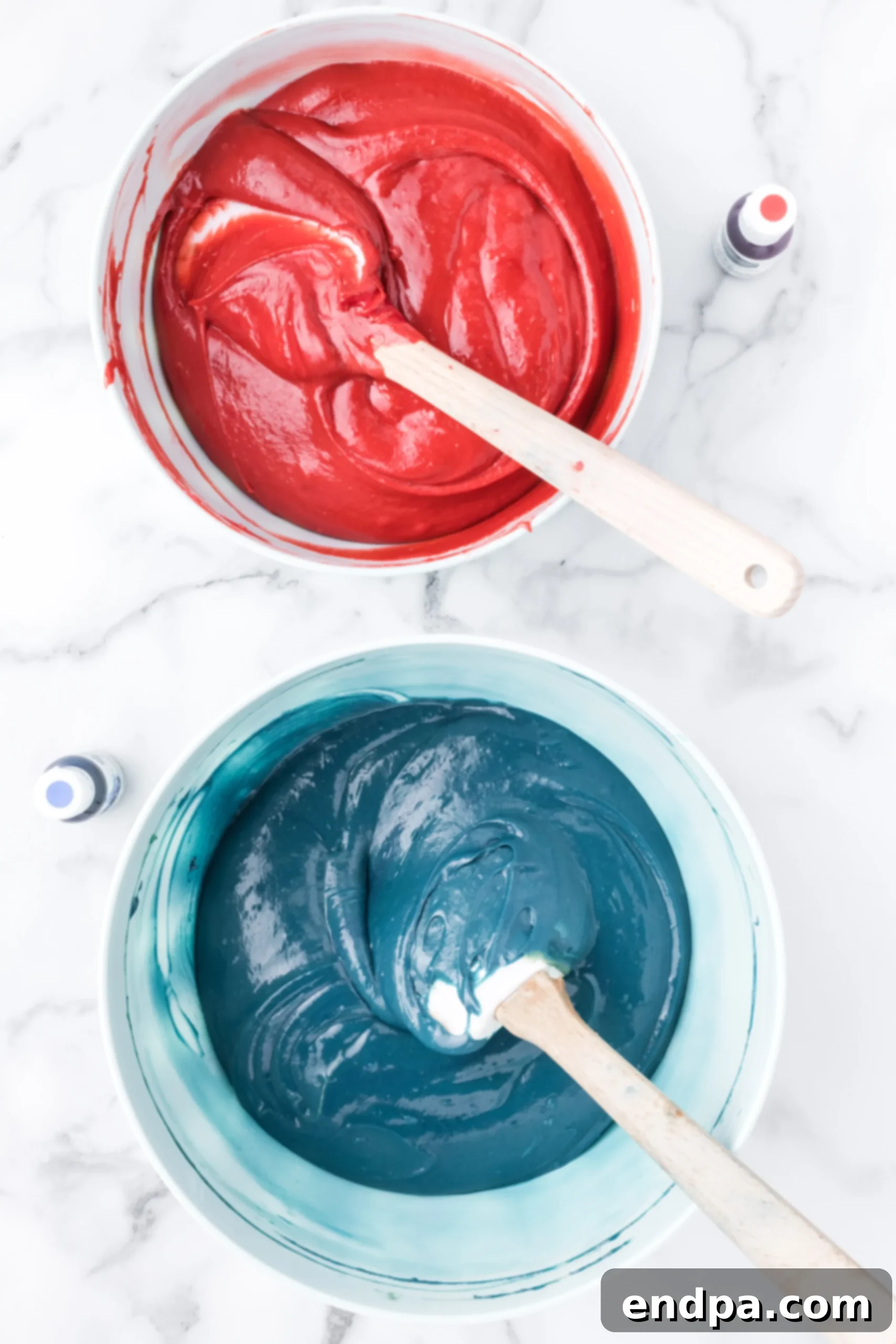 Batter in separate bowls with blue and red food coloring.