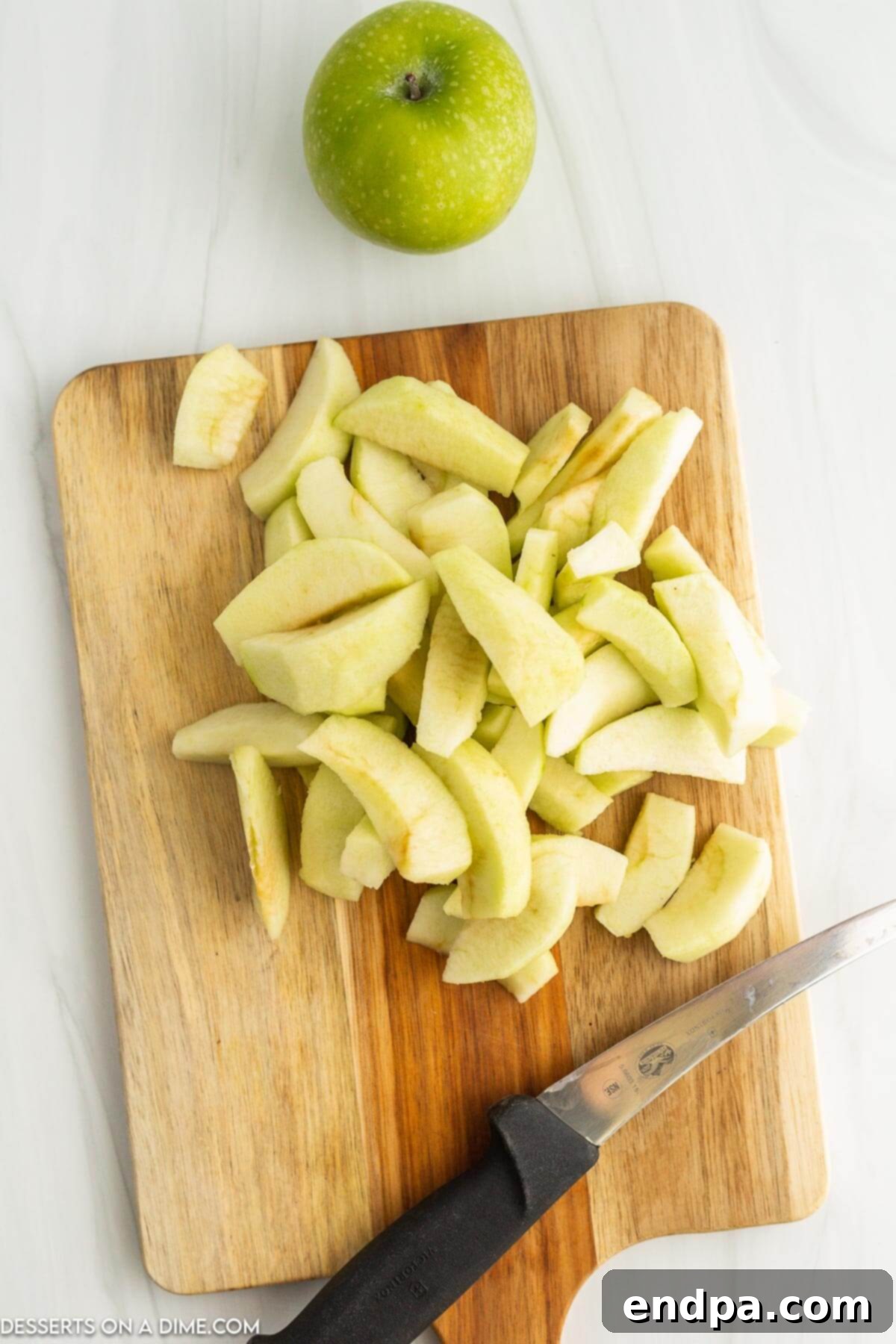 Fresh apples, peeled, cored, and sliced into uniform wedges on a cutting board, ready for cooking.