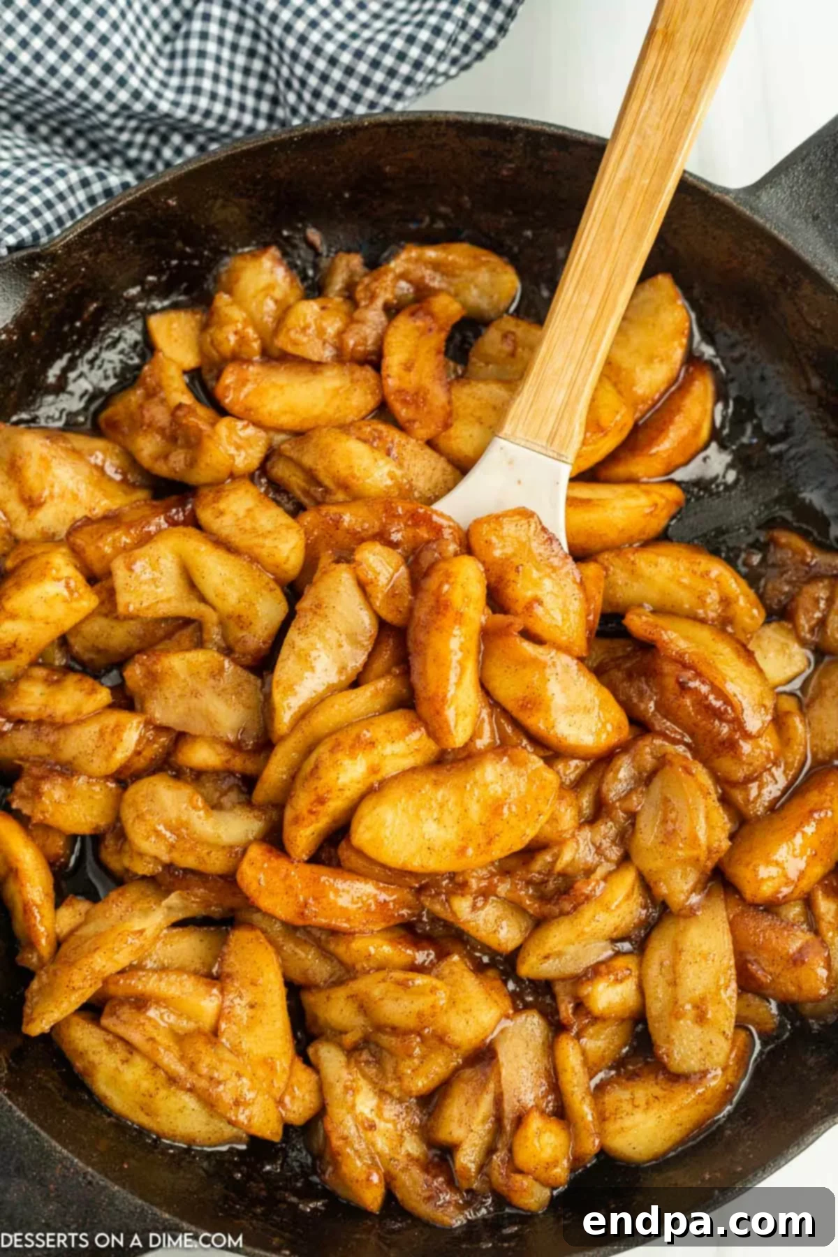 A close-up of finished Cracker Barrel fried apples, glistening with a sweet, spiced caramel sauce in a cast iron skillet.
