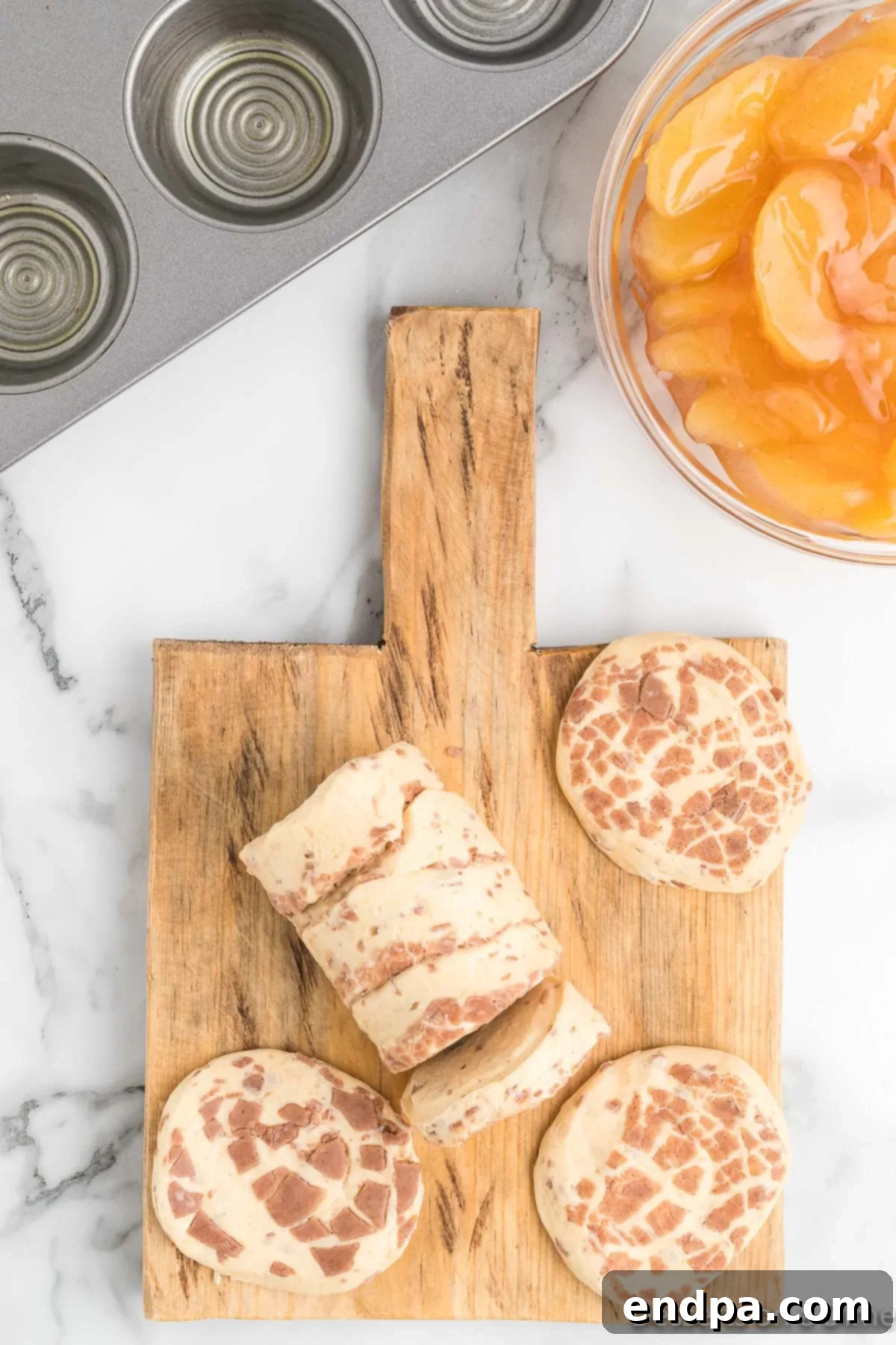 Cinnamon rolls spread out on a cutting board, ready for preparation.