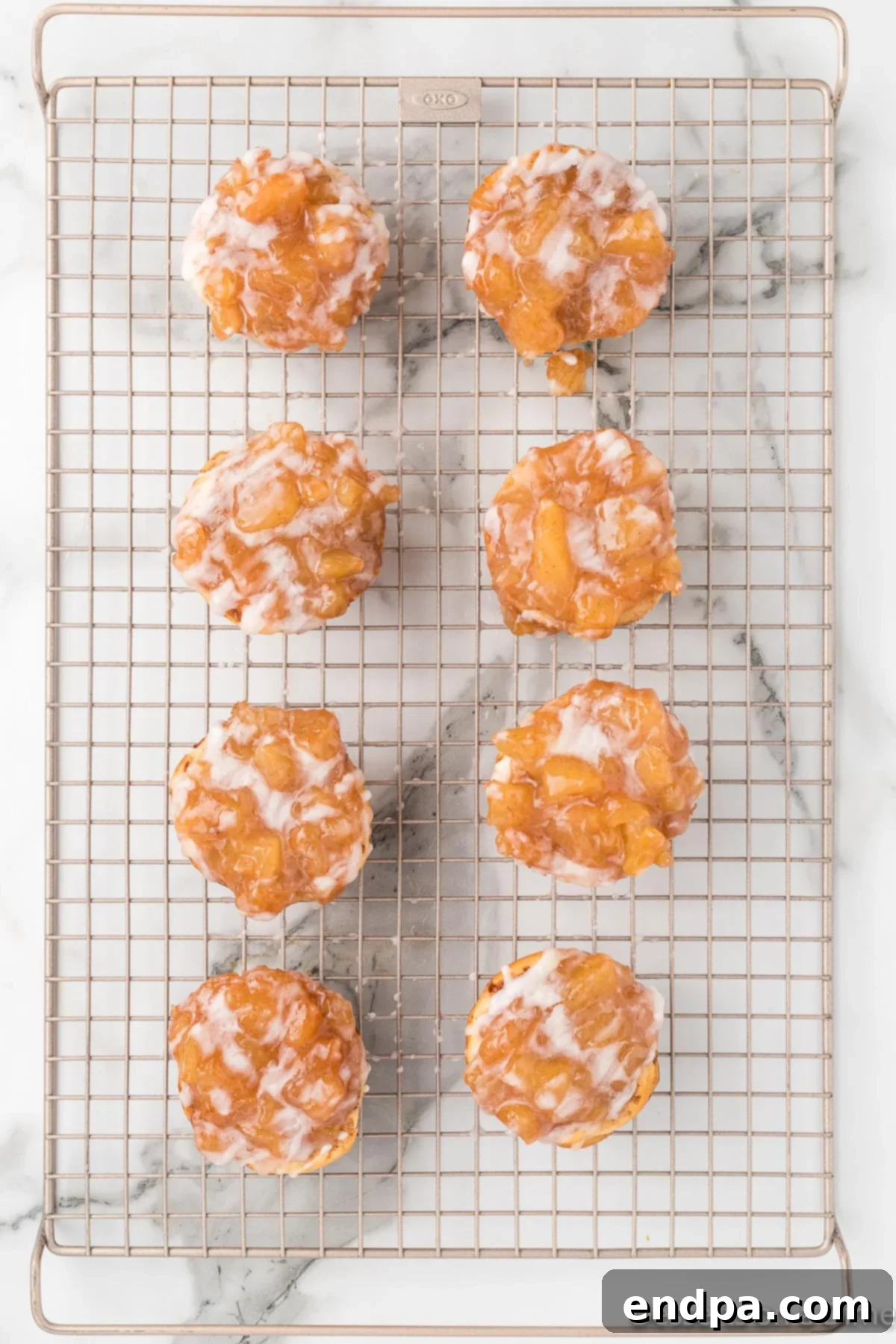 Warm Cinnamon Roll Apple Pie Cups cooling on a wire rack, topped with a sweet glaze.