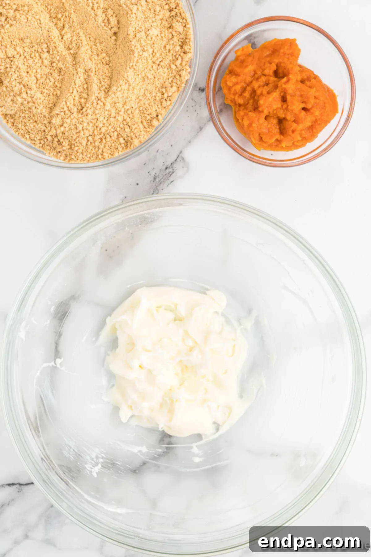 Cream cheese and powdered sugar being blended in a mixing bowl.