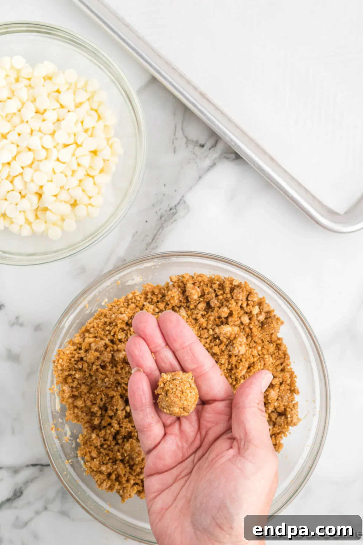 A hand rolling the pumpkin truffle mixture into a small ball.
