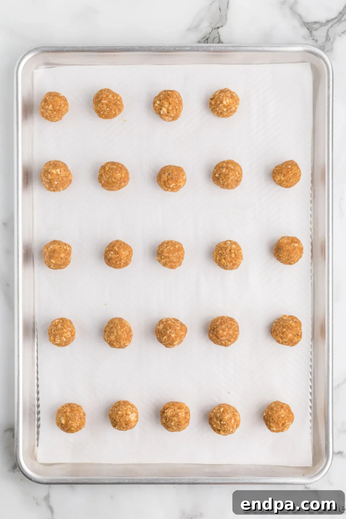 Rolled pumpkin truffle balls neatly arranged on a parchment-lined baking sheet.