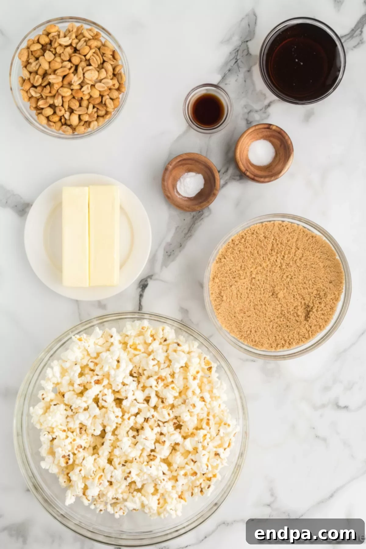 A flat lay of fresh ingredients including brown sugar, butter, corn syrup, and popped popcorn, laid out for making butter toffee popcorn.