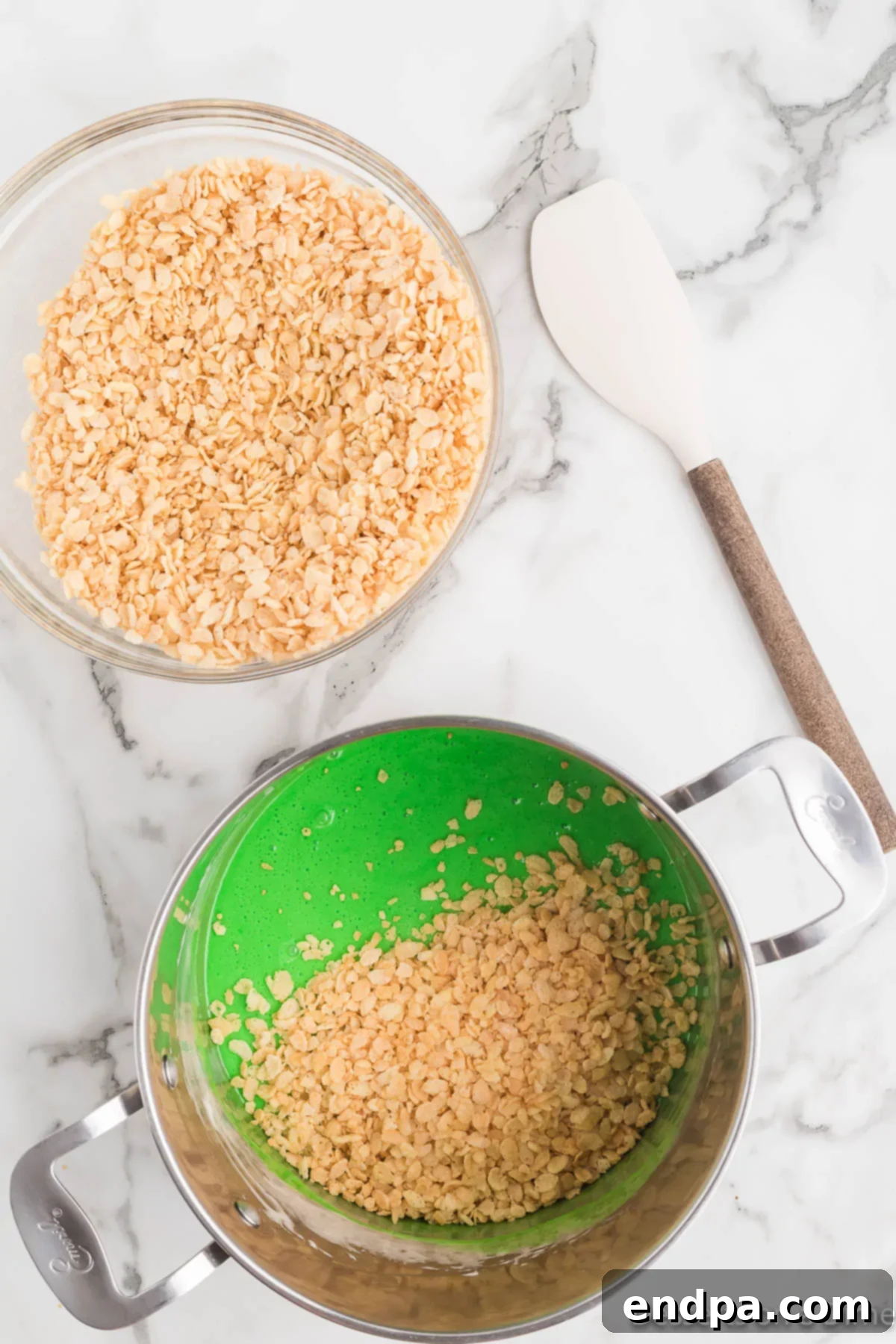 Rice Krispie cereal being stirred into the green marshmallow mixture until fully coated.
