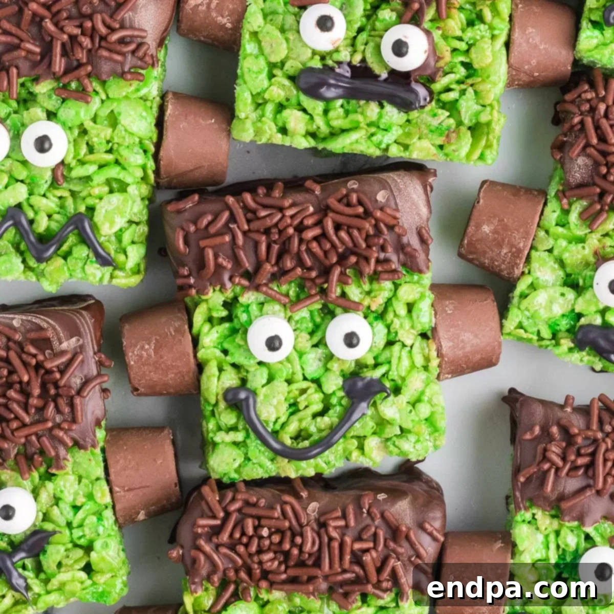 Close-up of a completed Frankenstein Rice Krispie Treat, showing the green color, chocolate hair, candy eyes, and Rolo bolts.