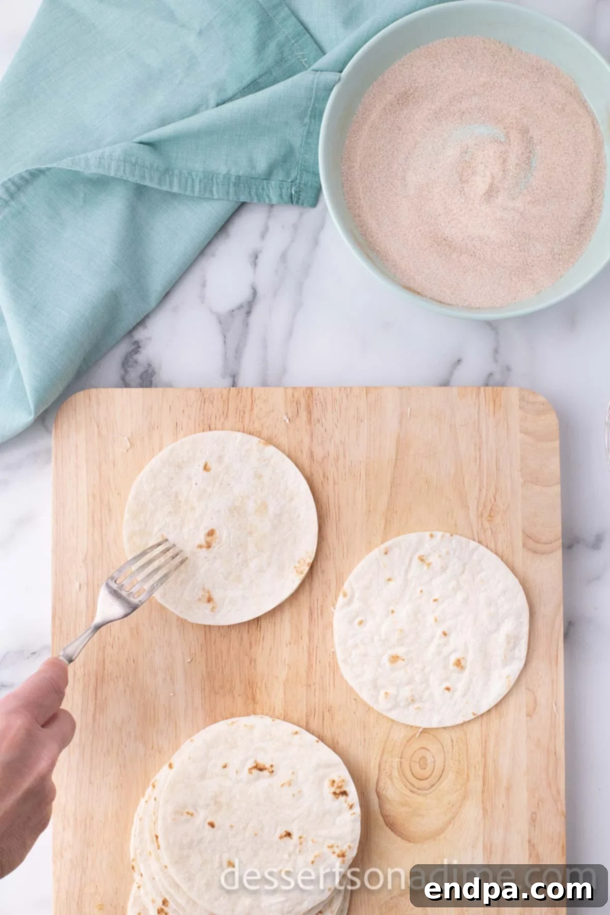 Tortillas on cutting board poked with a fork. 