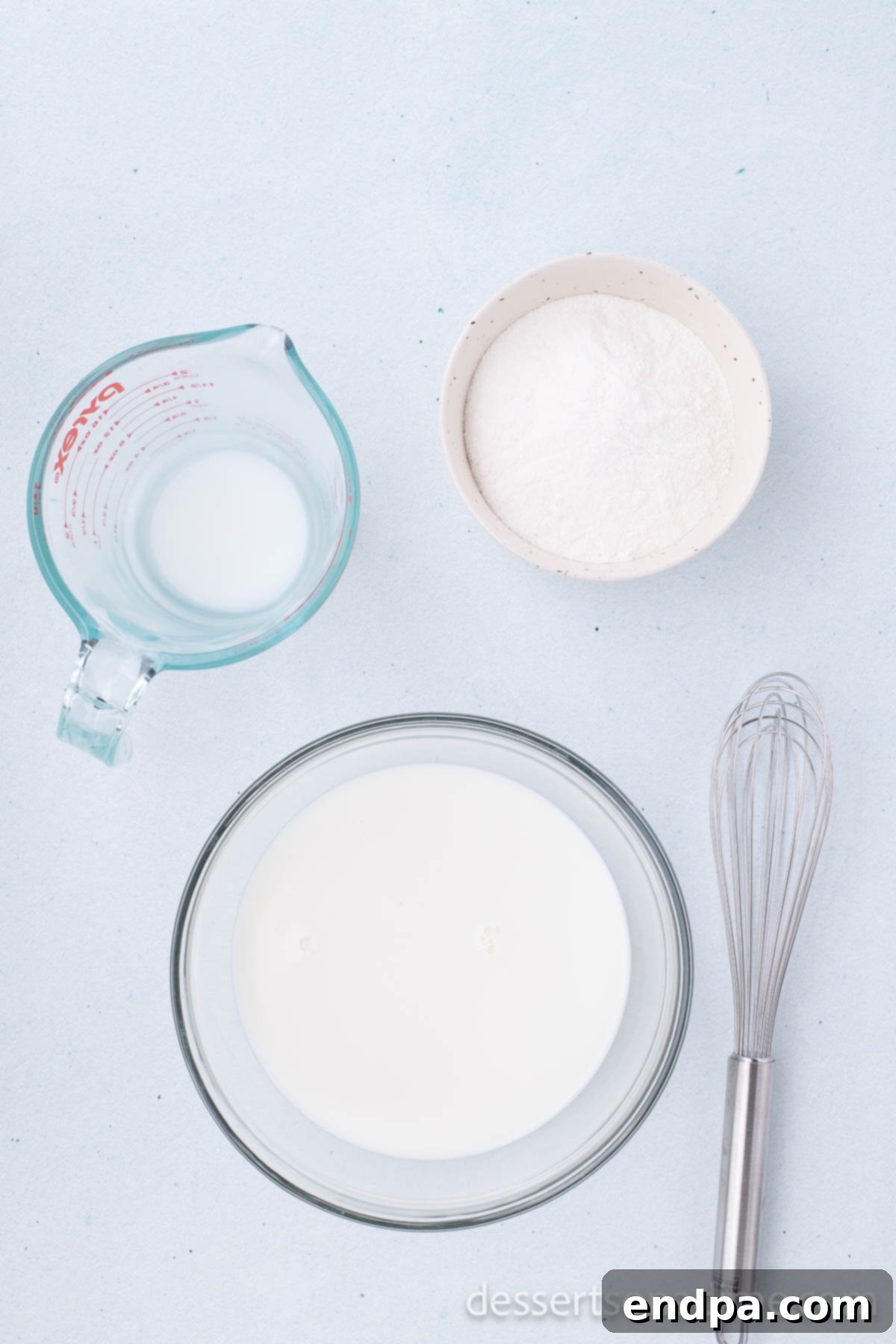 Pudding mix and cold milk being combined in a medium bowl using a whisk.