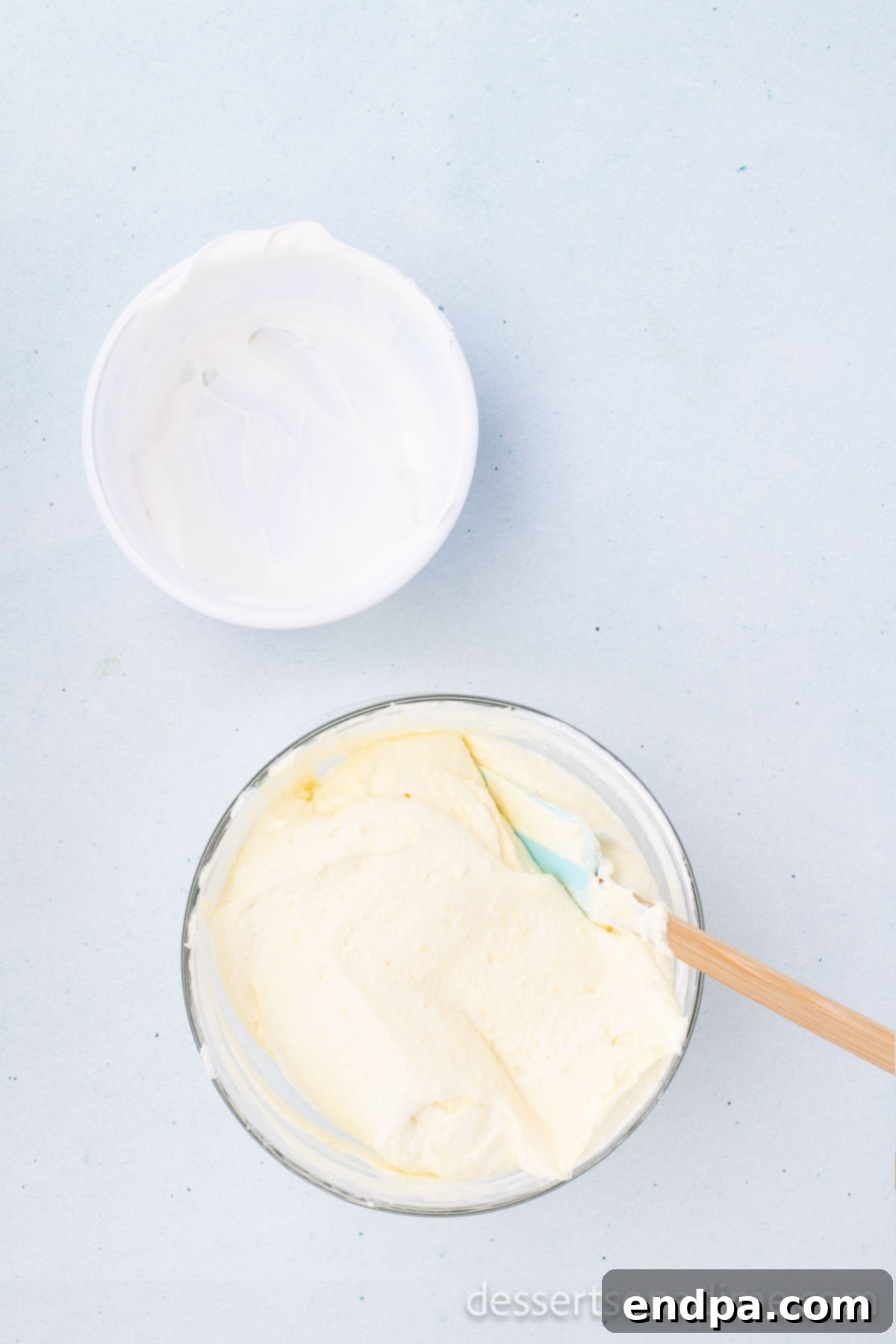 Thawed whipped topping being gently folded into the chilled pudding mixture.