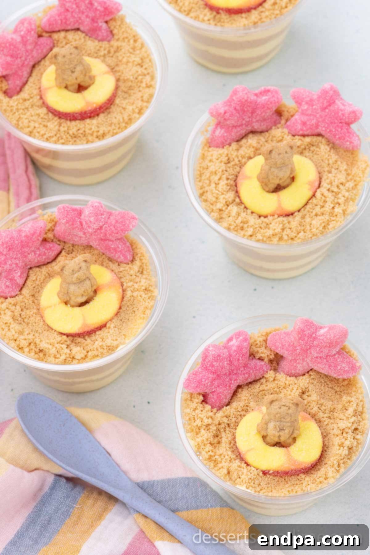 Close-up of Sand Pudding Cups, perfectly decorated with candy, showing the distinct layers of creamy pudding and golden cookie crumbs.
