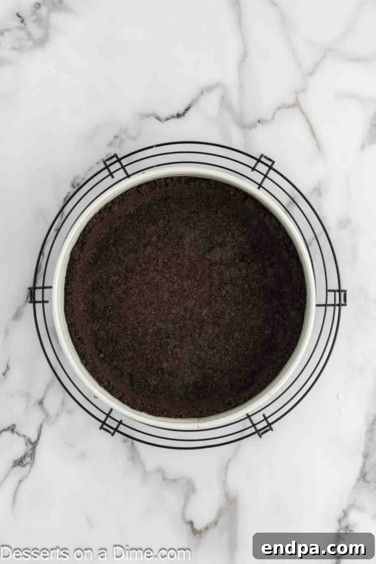 Pressing crushed Oreo crust into a springform pan