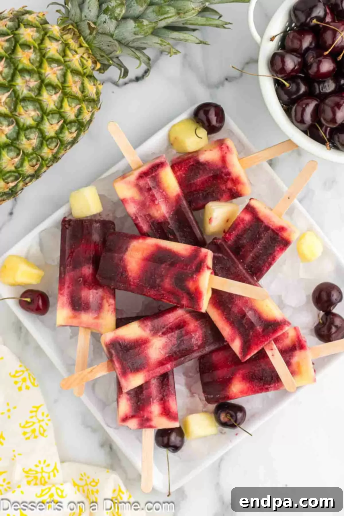 Cherry Pineapple Popsicles on a platter with ice