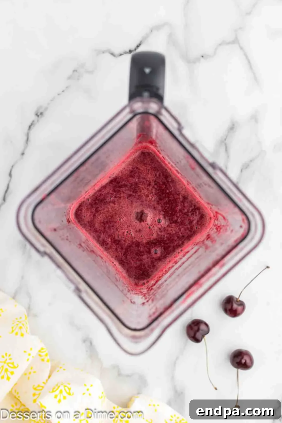 Blender with cherries and ingredients blended together.