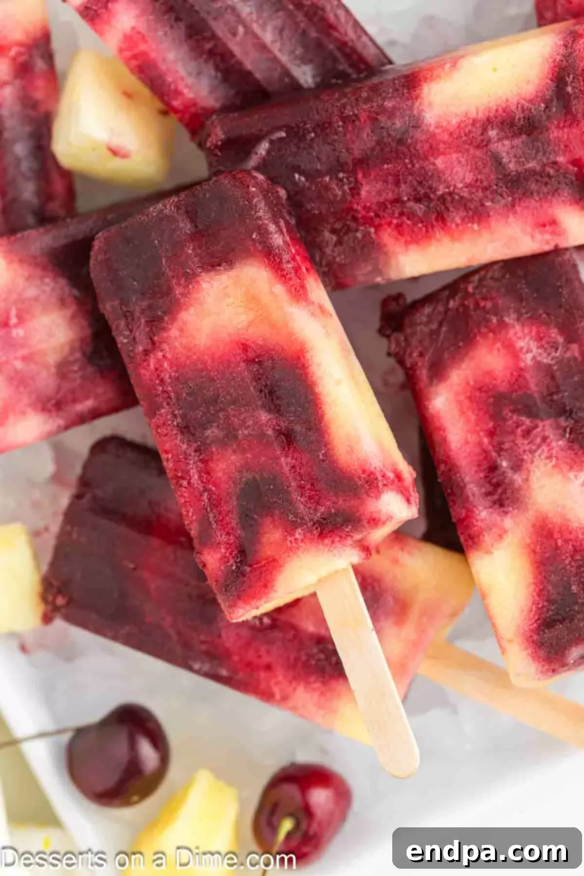 Cherry Pineapple Popsicles on a platter with ice.