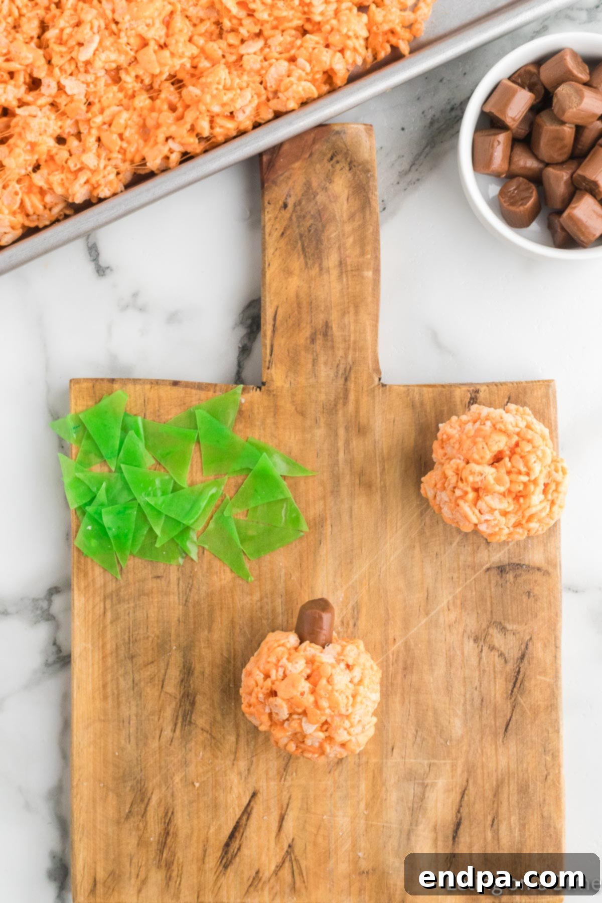 Pumpkin Patch Krispie Treats 12 The cooled Rice Krispies mixture being formed into small, round pumpkin shapes by hand.