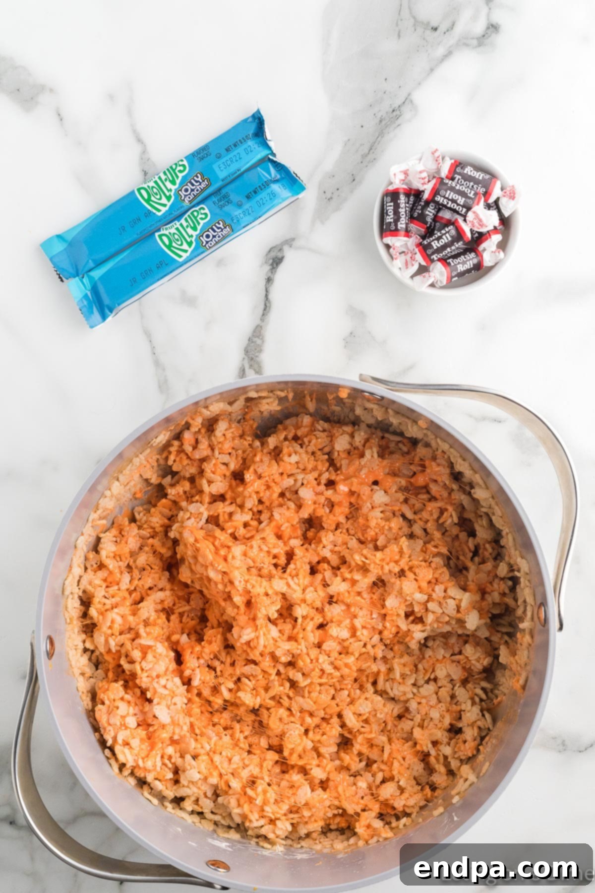Pumpkin Patch Krispie Treats 10 Rice Krispies cereal being folded into the orange marshmallow mixture in a large pan.