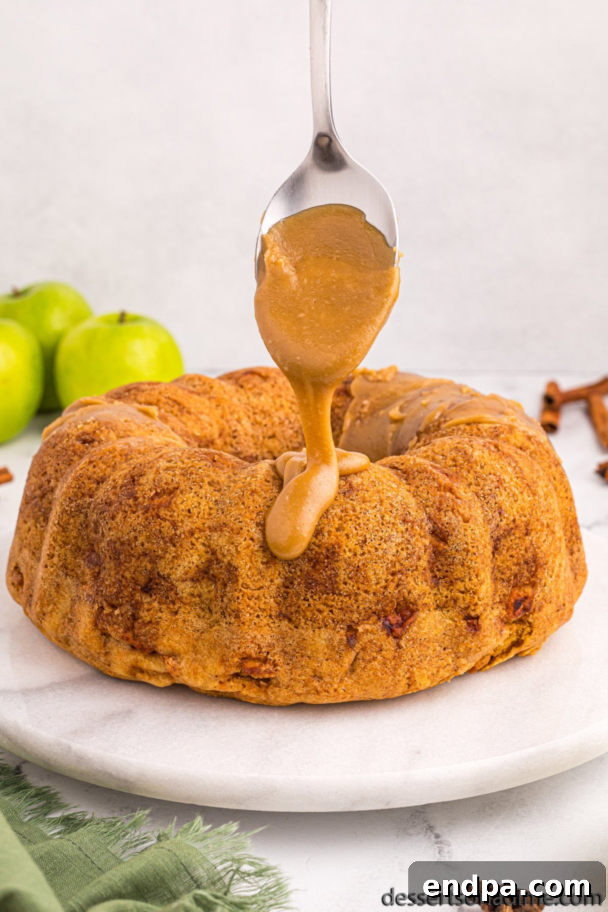 Brown sugar glaze being spooned over the cooled apple bundt cake.