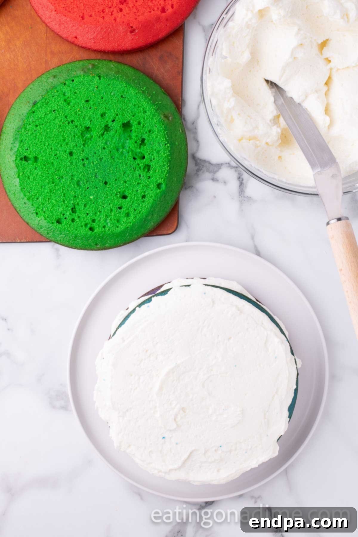 Kaleidoscope Delight 10 A Rainbow Cake in progress, with multiple colorful layers stacked neatly, each separated by a thick, smooth layer of white buttercream frosting, demonstrating the systematic assembly process.