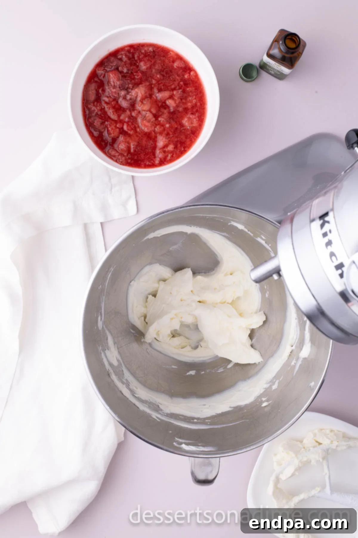 Velvety Strawberry Cream Cheese Frosting 5 Softened cream cheese being beaten until smooth and creamy in a mixing bowl.