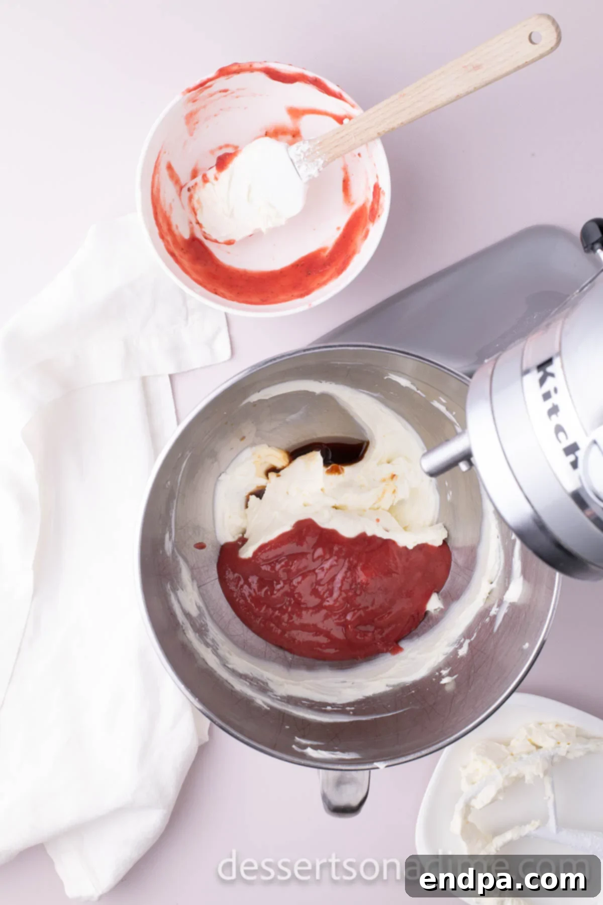 Velvety Strawberry Cream Cheese Frosting 6 The cooled strawberry puree being slowly added to the creamed butter and cream cheese mixture.