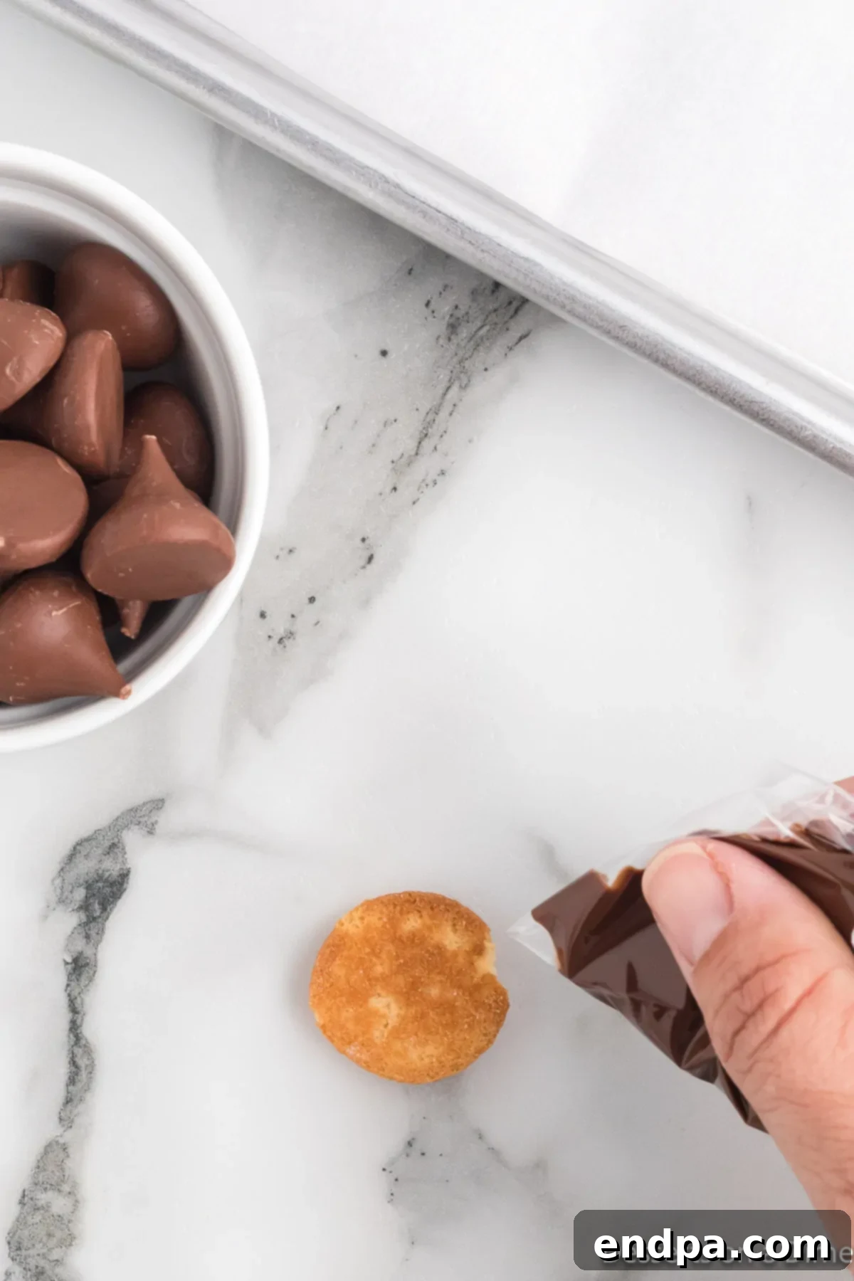 Acorn Chocolate Treasures 5 Melted chocolate in a ziploc bag being piped on to a vanilla wafer.