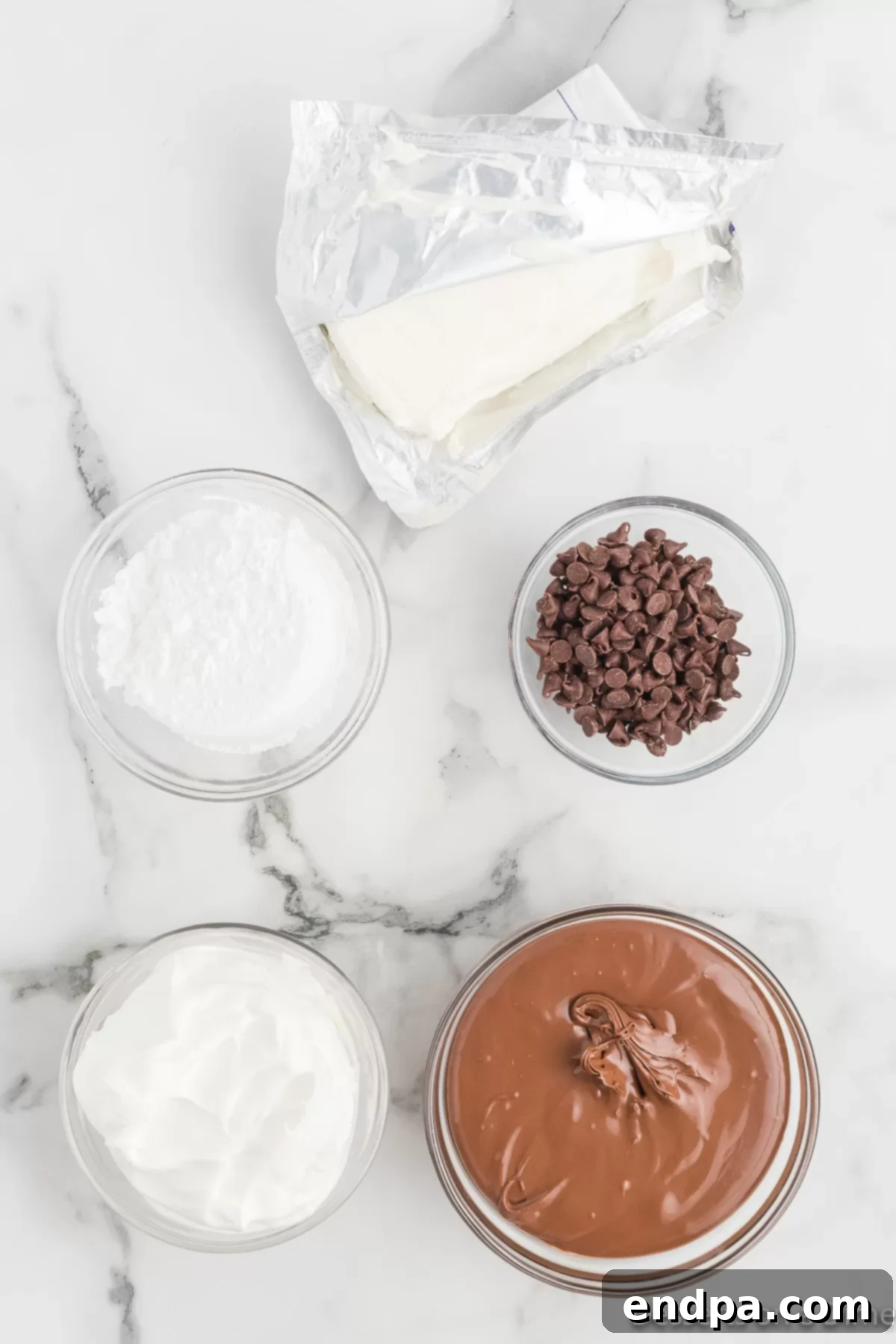 Individual ingredients for Nutella dip laid out: a jar of Nutella, a bag of powdered sugar, a tub of Cool Whip, a block of cream cheese, and a bag of mini chocolate chips