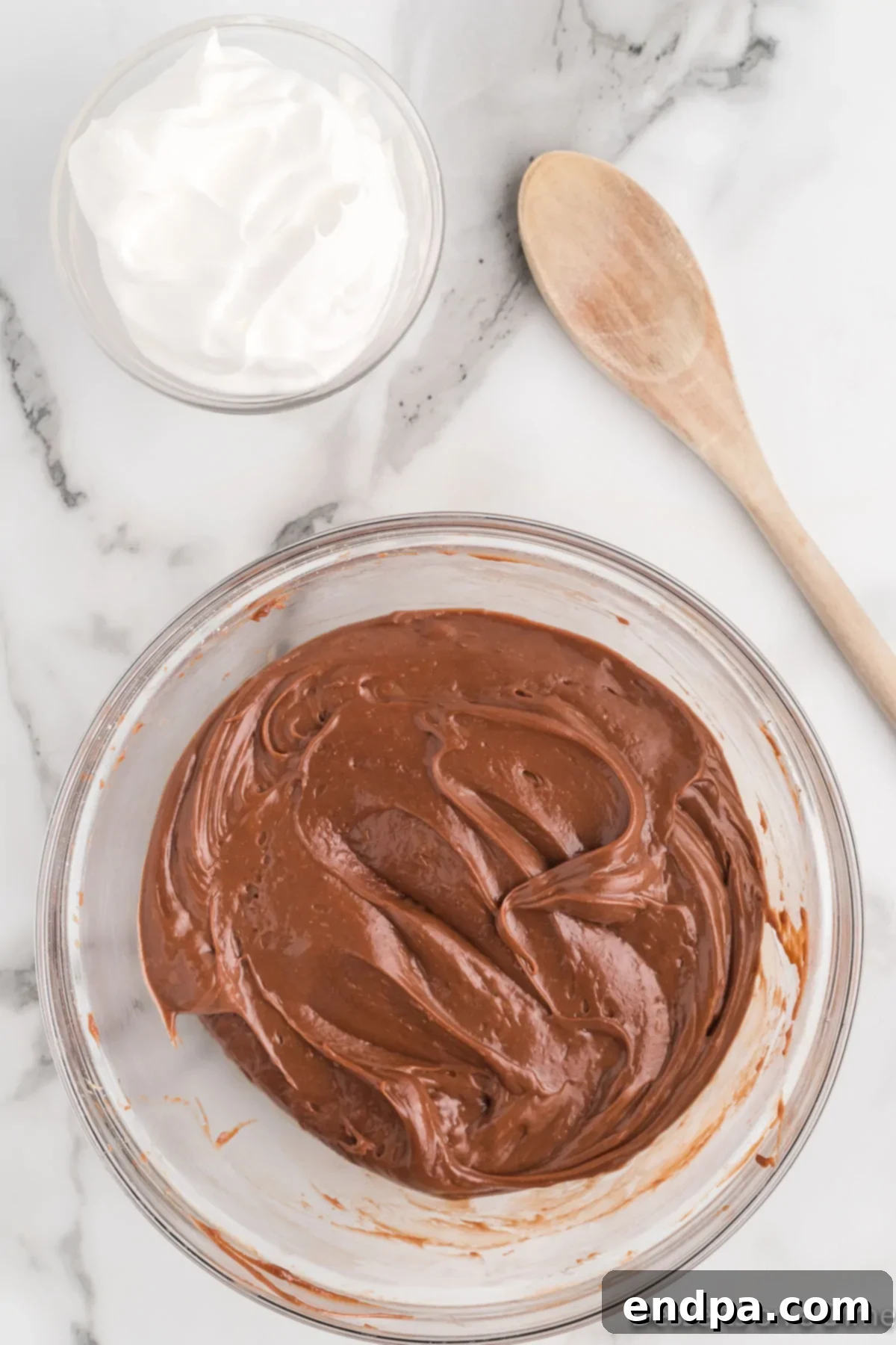 Nutella and powdered sugar added to the bowl with cream cheese, ready for mixing