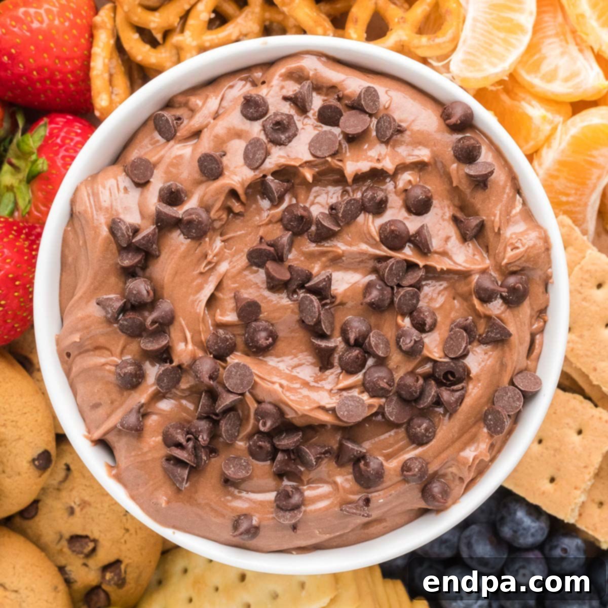 Delicious Nutella Dip in a white bowl with strawberries and pretzels on the side