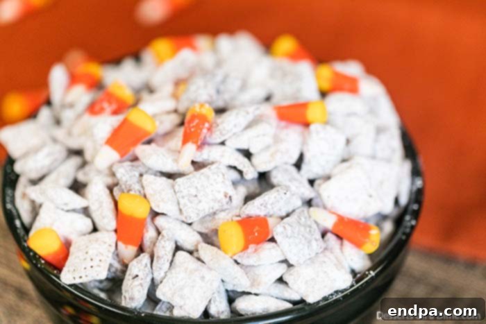 Finished Halloween Puppy Chow with candy corn and candy eyeballs in a black serving bowl, ready for a party.