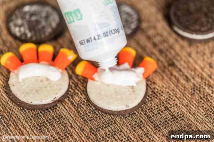 Gobble Gobble Oreo Delights 3 The Oreo cookie base with candy corn feathers now has dabs of white pre-made icing applied over the base of the candy corn, ready to adhere the other half of the cookie.