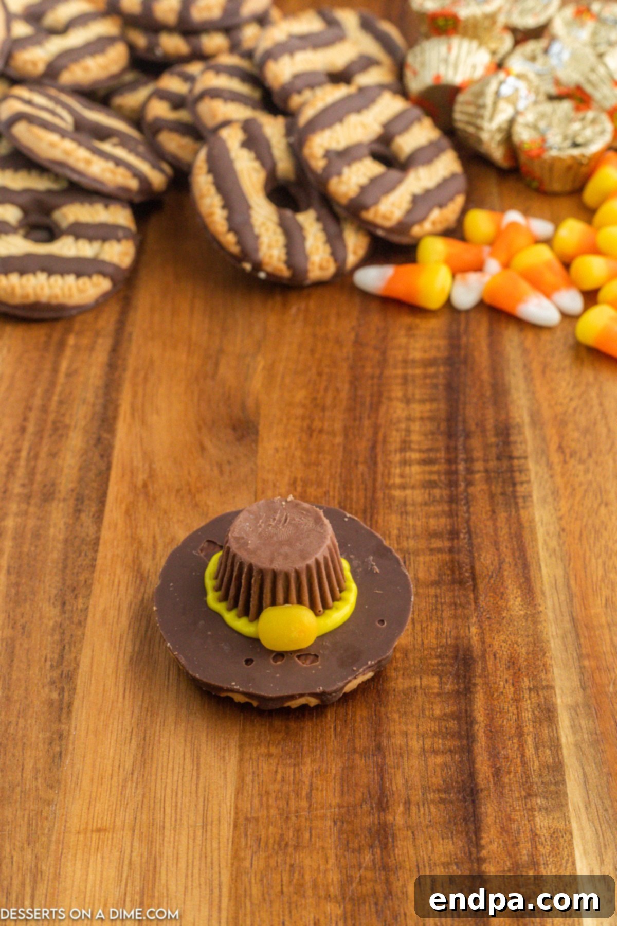 Orange portion of candy corn attached to the front of the yellow icing brim, forming the buckle.
