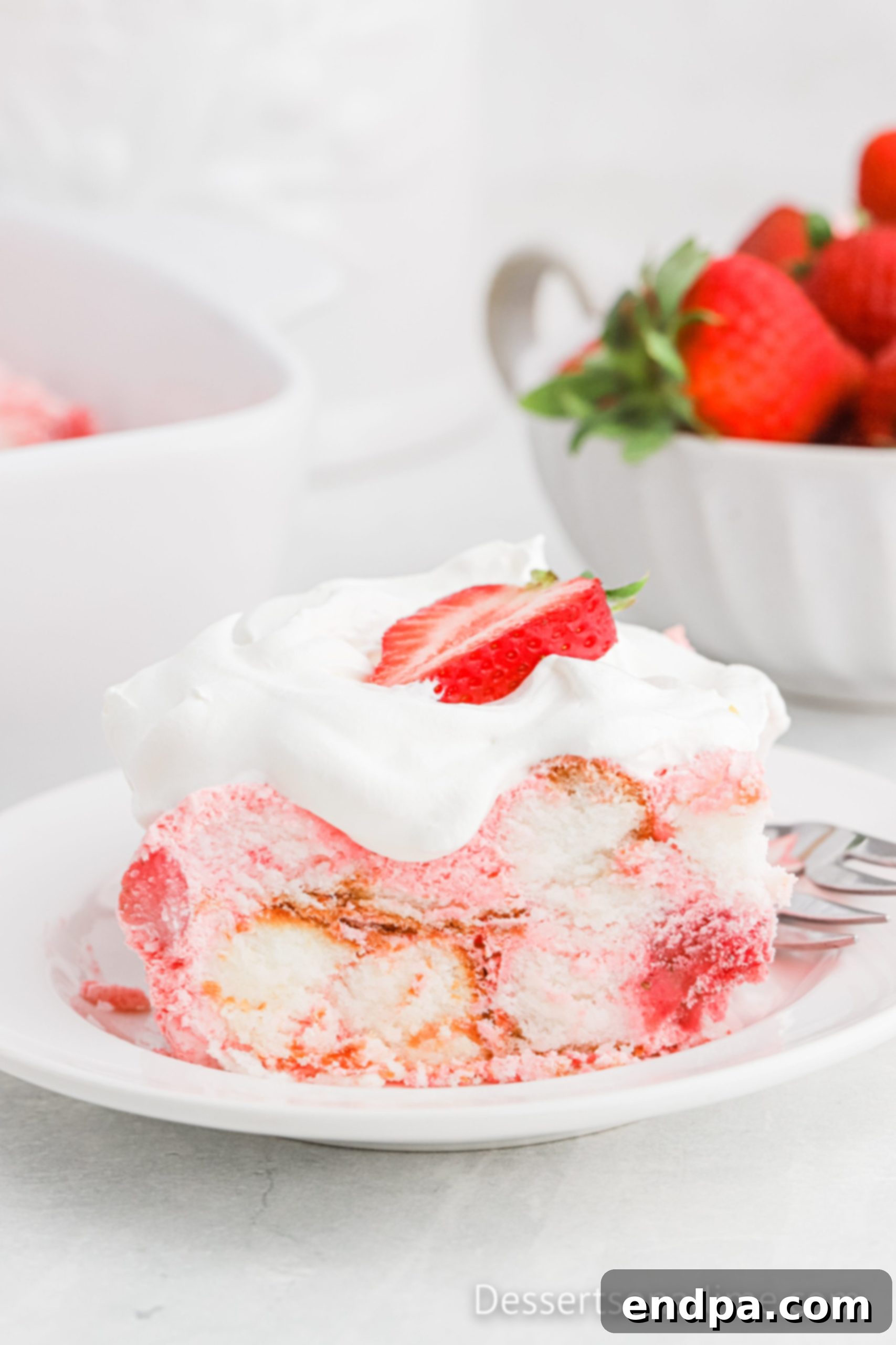 Strawberry Angel Food Cake served on a white plate, showcasing its layers and fresh strawberry garnish.