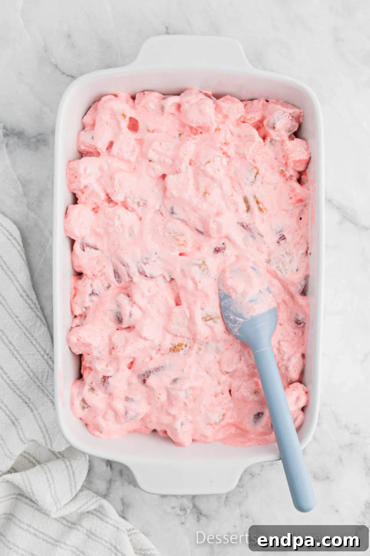 The strawberry angel food cake mixture spread evenly into a 9x13 inch glass baking dish, ready for chilling.