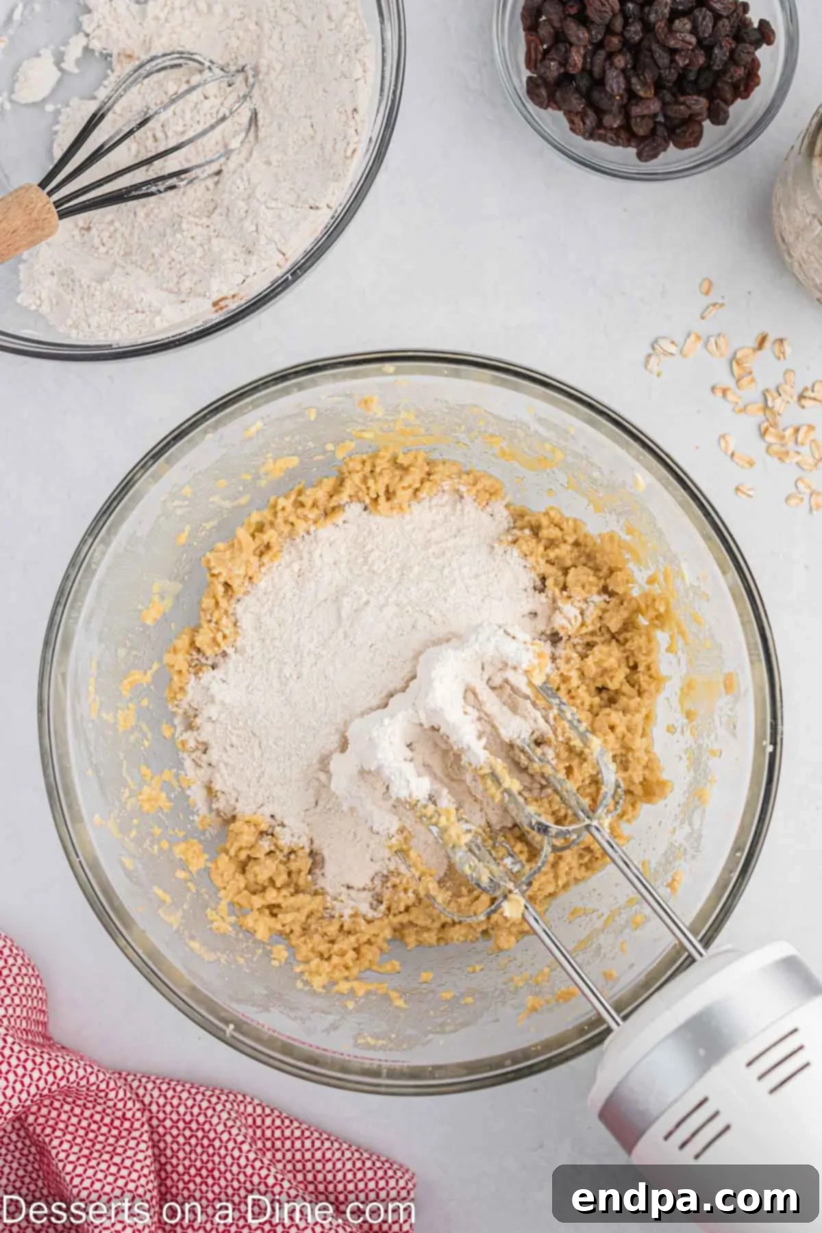 Classic Oatmeal Raisin Cookies 5 Dry ingredients being added to the wet ingredients and combined in a bowl to form cookie dough.