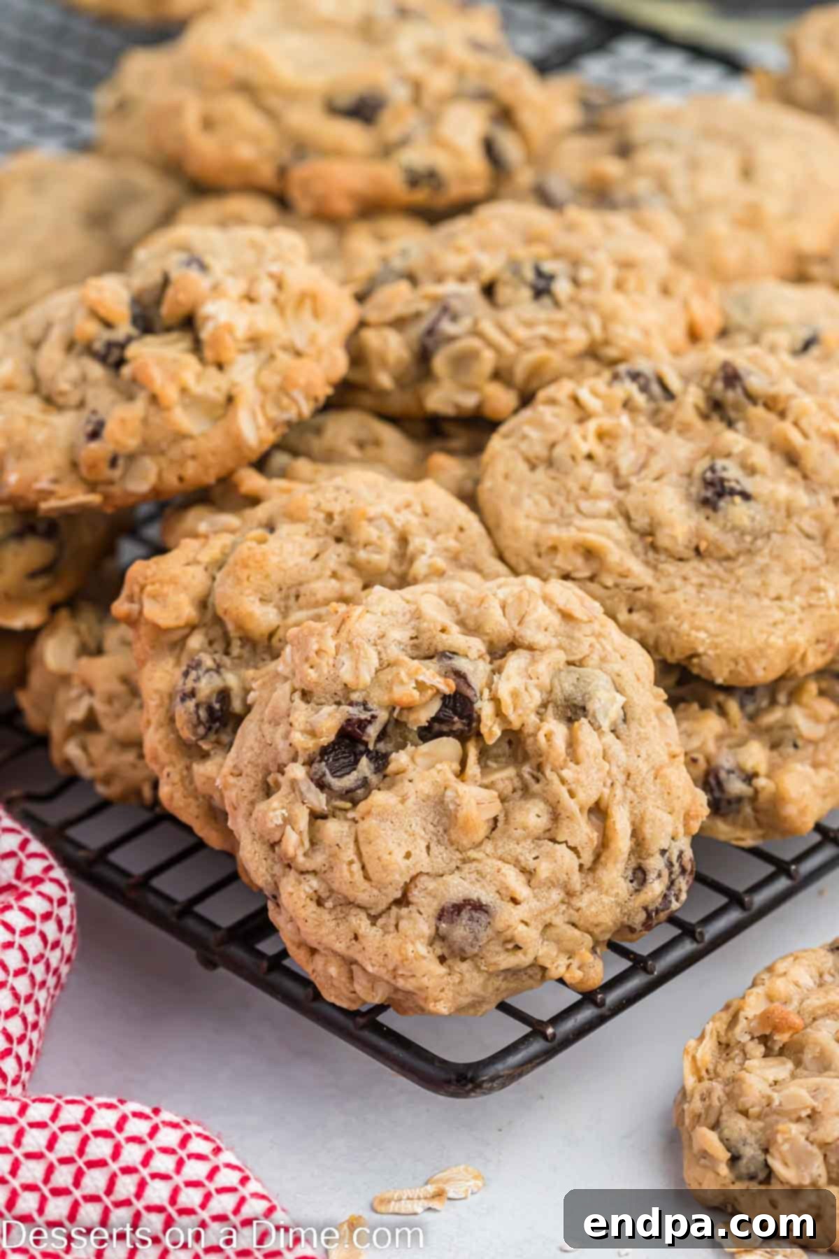 This is the best recipe for soft and chewy Oatmeal raisin cookies. They are so decadent and everyone will think you bought them at a bakery. Make these moist homemade cookies today for an easy treat. A close-up of oatmeal raisin cookies stacked on a cooling rack, highlighting their texture and plump raisins.