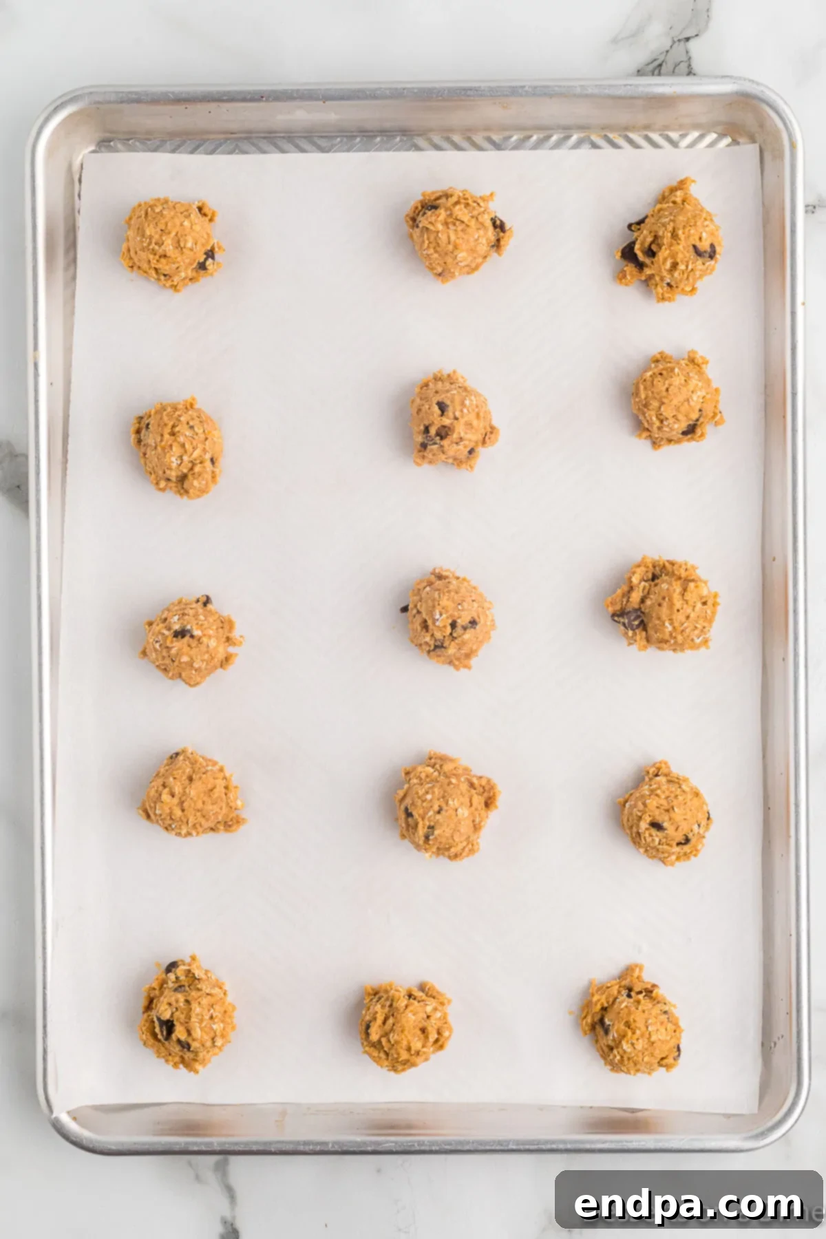 Golden Sweet Potato Cookies 12 Portioned sweet potato cookie dough balls arranged on a parchment-lined baking sheet.