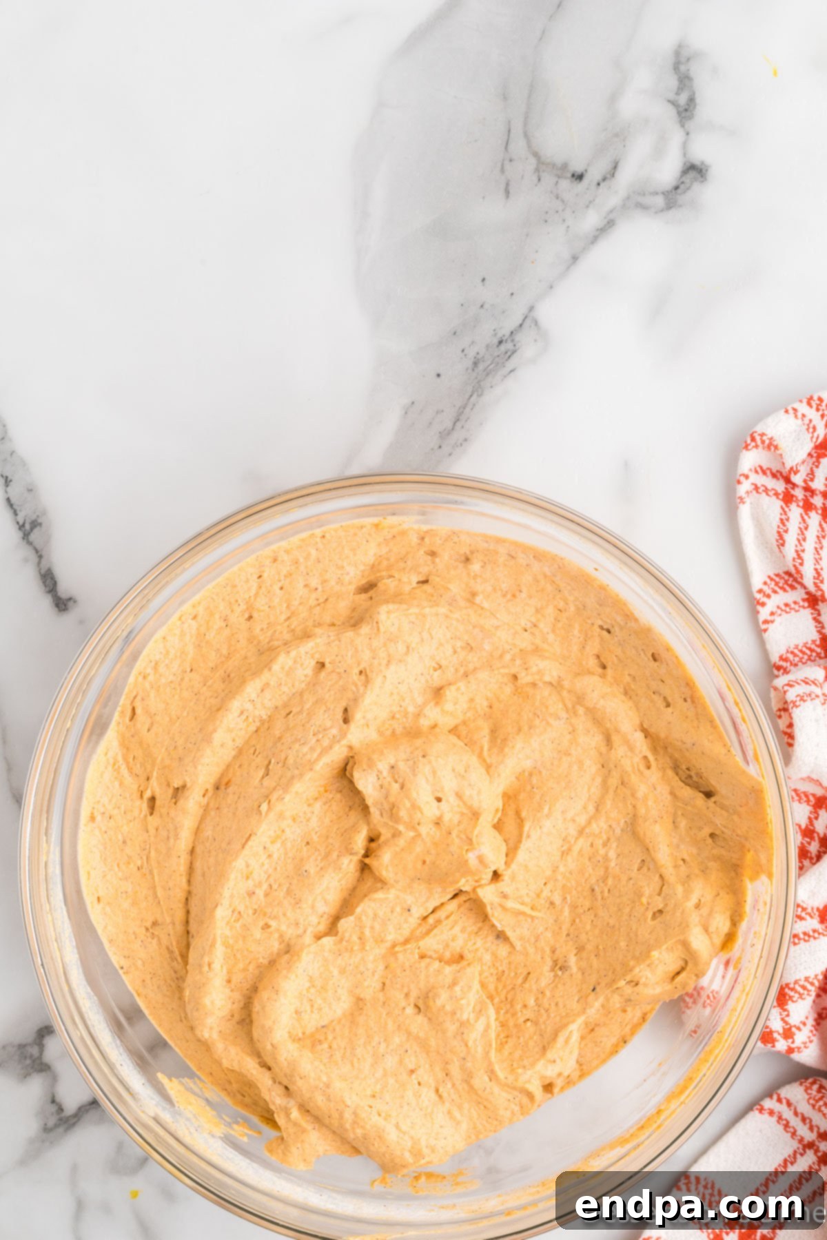 Autumn Pumpkin Fluff Dip 6 Thawed Cool Whip being gently folded into the pumpkin and spice mixture in a bowl, demonstrating the technique for achieving a light and fluffy dip.