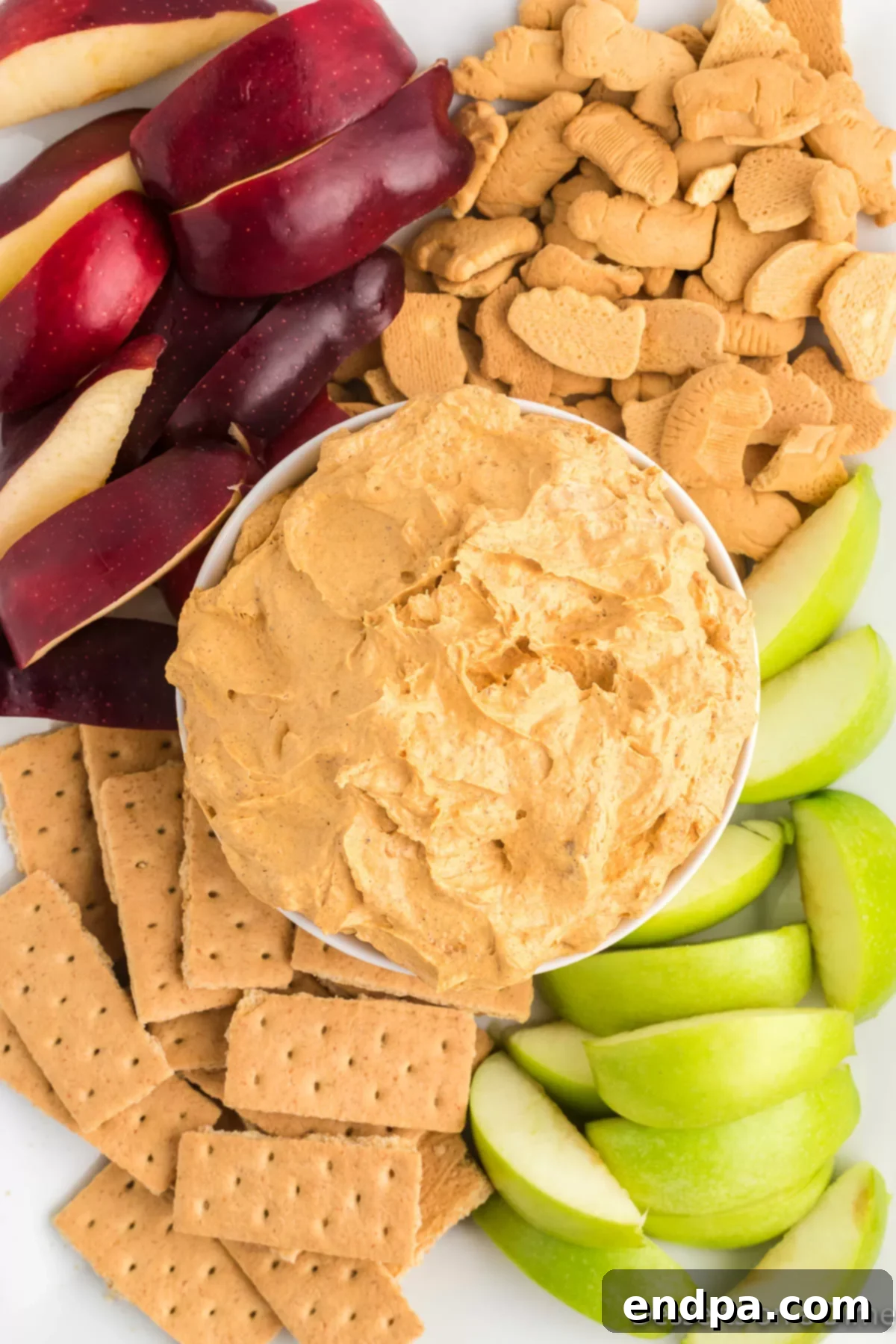 Autumn Pumpkin Fluff Dip 8 A vibrant platter showcasing a bowl of Pumpkin Dip with Cool Whip, surrounded by a colorful array of dippers including various fruits, cookies, and crackers, creating an inviting visual for fall entertaining.