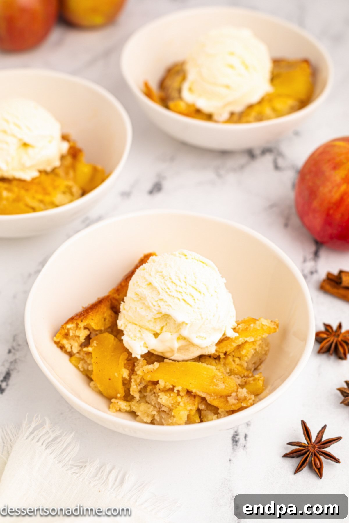Homestyle Apple Cobbler 2 Bowls of apple cobbler topped with vanilla ice cream, ready to be served.