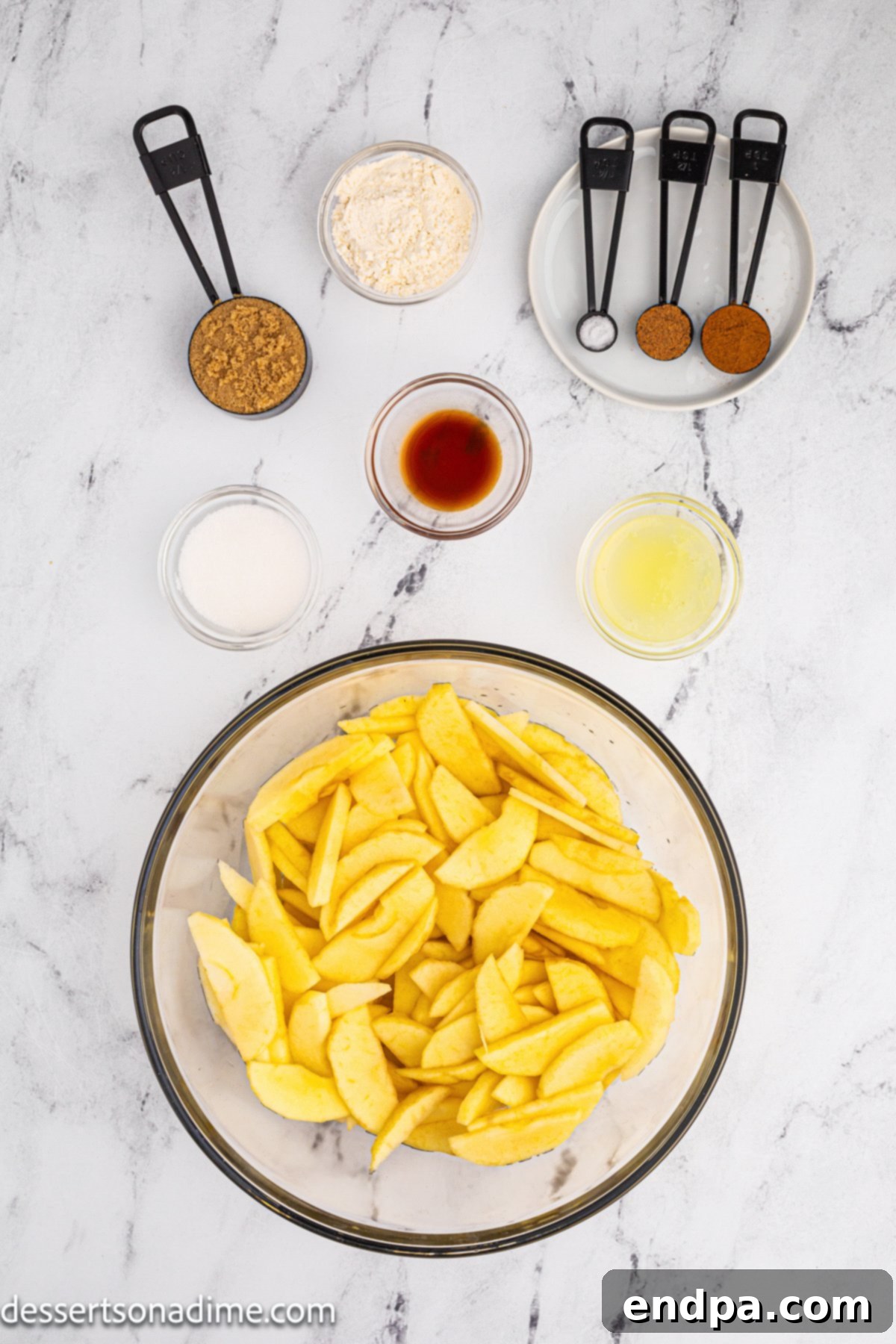 Homestyle Apple Cobbler 3 Ingredients for apple cobbler laid out: apples, brown sugar, granulated sugar, flour, lemon, cinnamon, nutmeg.