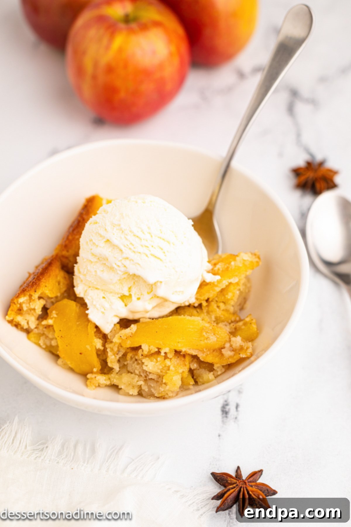 Homestyle Apple Cobbler 10 Bowls of apple cobbler topped with vanilla ice cream, served on a rustic wooden surface.