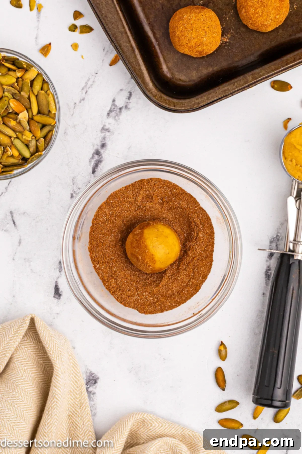 Cookie dough ball being rolled in the cinnamon-sugar mixture.