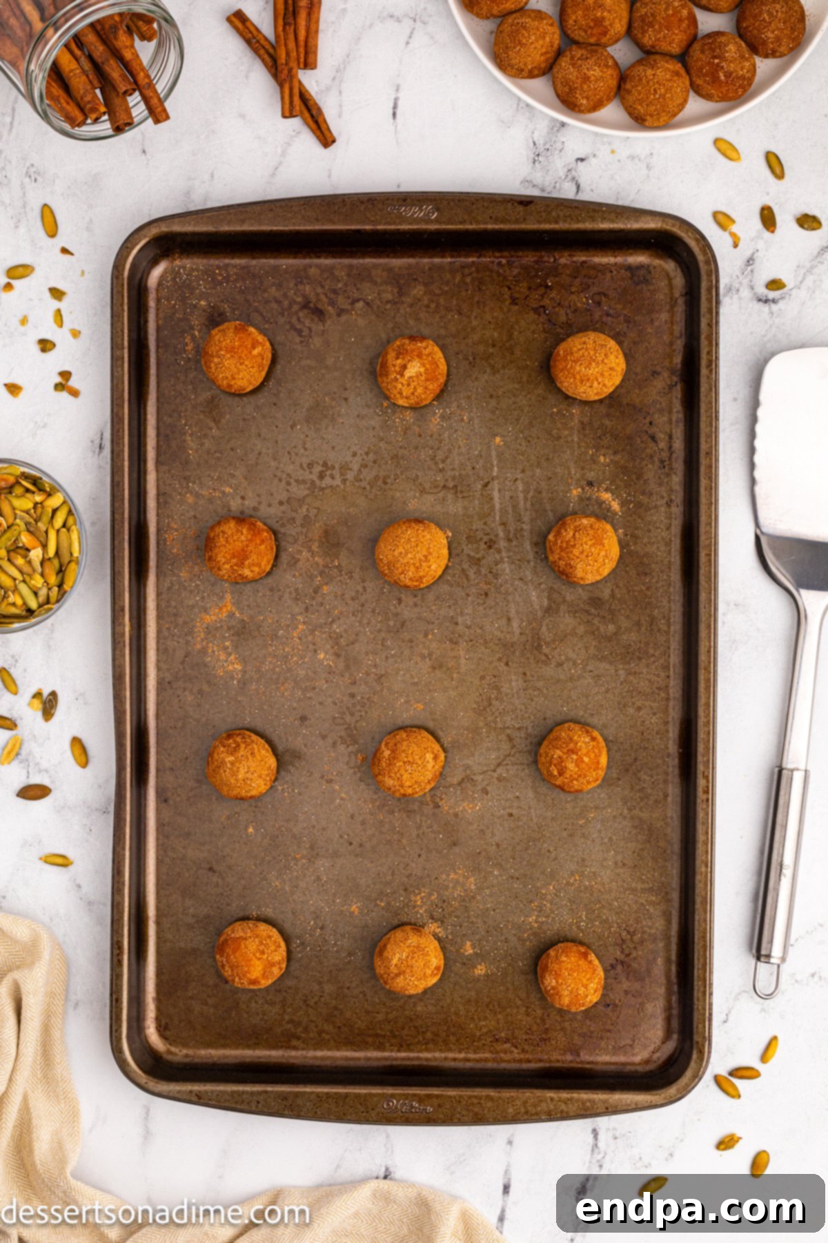 Coated cookie dough balls arranged on a baking sheet before baking.