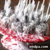 Spooktacular Cake Pops 4 Spider web cake pops with delicate white frosting webs on a dark background.