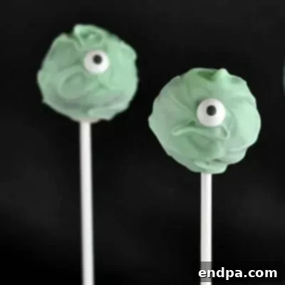 Spooktacular Cake Pops 5 One-eyed monster cake pops in various bright colors, each with a single large candy eye.